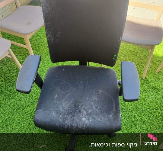 כיסא משרדי שחור עם כתמים על דשא ירוק